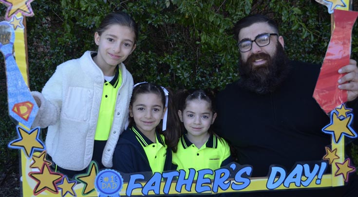 Father and three daughters from Holy Spirit Primary St Clair. Everyone is holding a sign which reads Happy Fathers Day